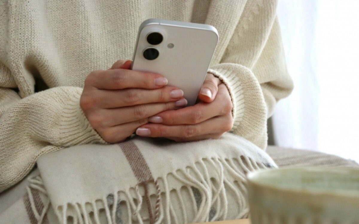 スマホを両手で優しく包み込んでいる女性の手元