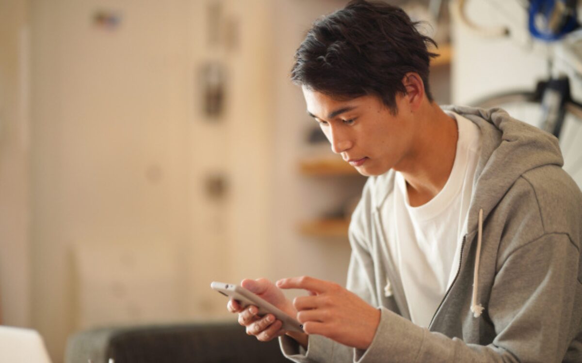 スマホのアプリを見つめながら自分を見つめ直しをする男性